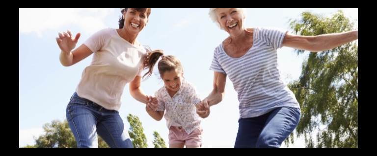 A girl playing on a trampoline with her mother and grandmother